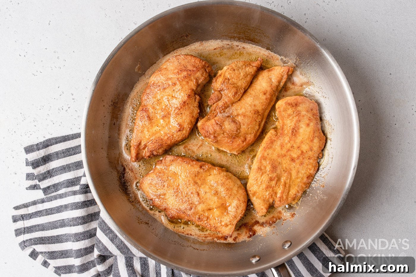 chicken cooking on a pan with butter and oil