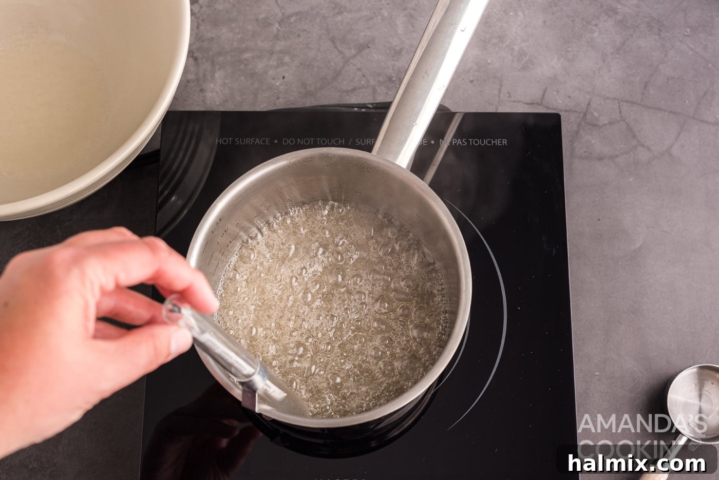 candy thermometer in a saucepan of sugar water
