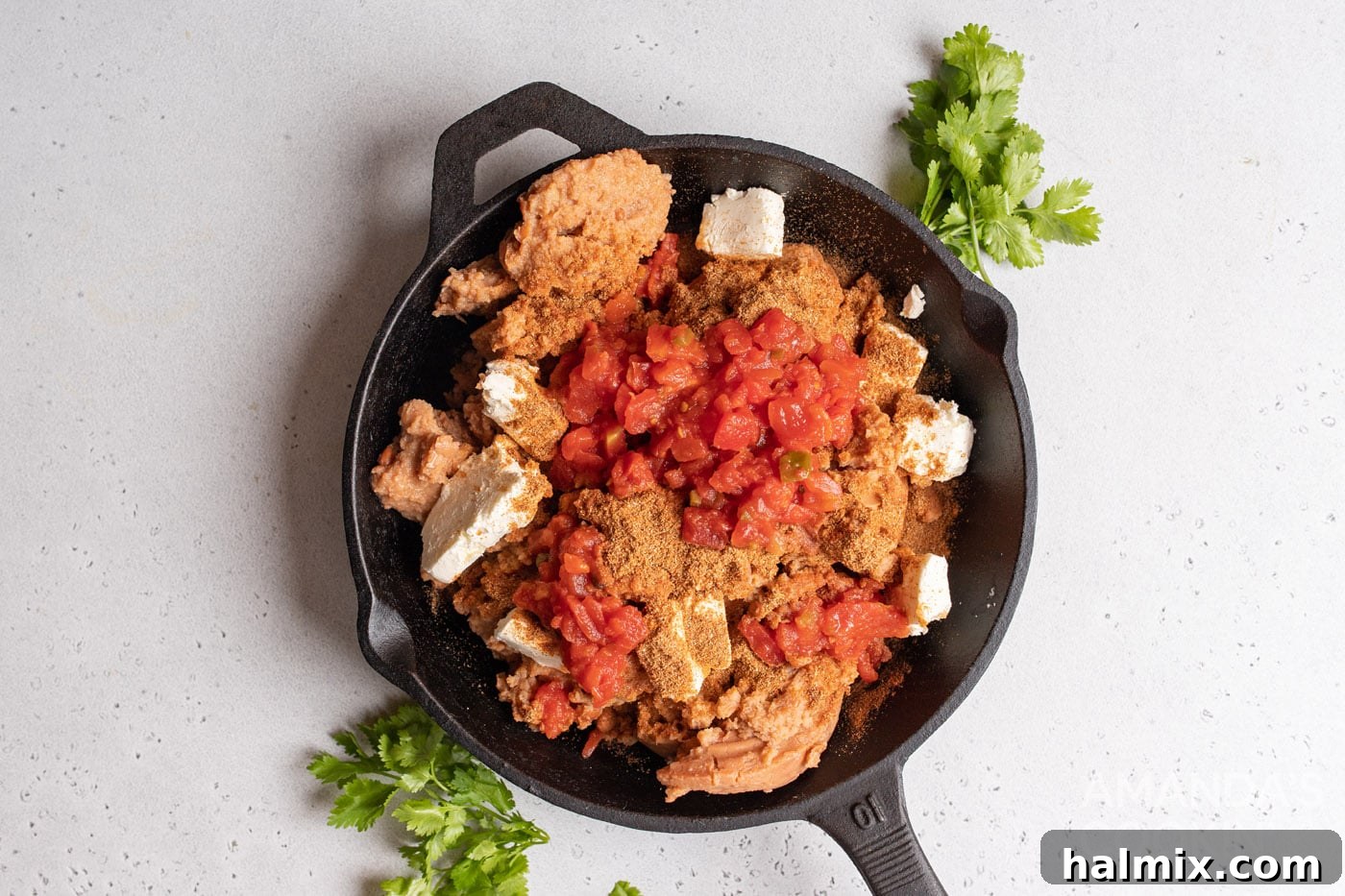 refried beans, tomatoes, cream cheese, and taco seasoning in a skillet