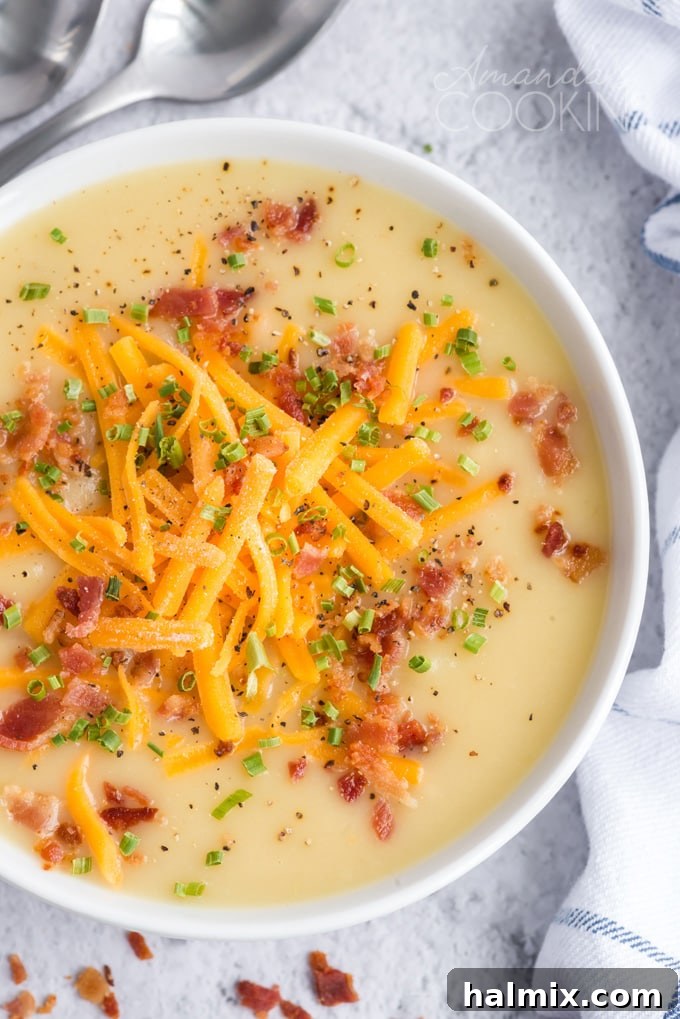 Pure comfort food, this creamy potato cheese soup is topped with crumbled bacon and chives. Made with extra sharp cheddar cheese for the best flavor. close up overhead photo of cheddar potato soup