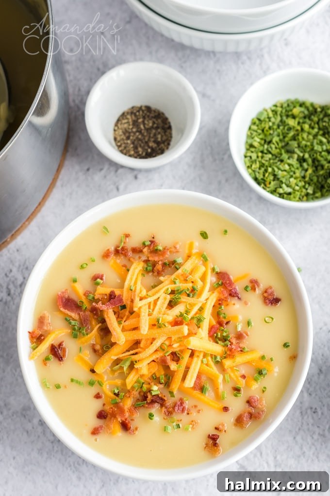Pure comfort food, this creamy potato cheese soup is topped with crumbled bacon and chives. Made with extra sharp cheddar cheese for the best flavor. bowl of potato cheese soup with bowl of chives behind it