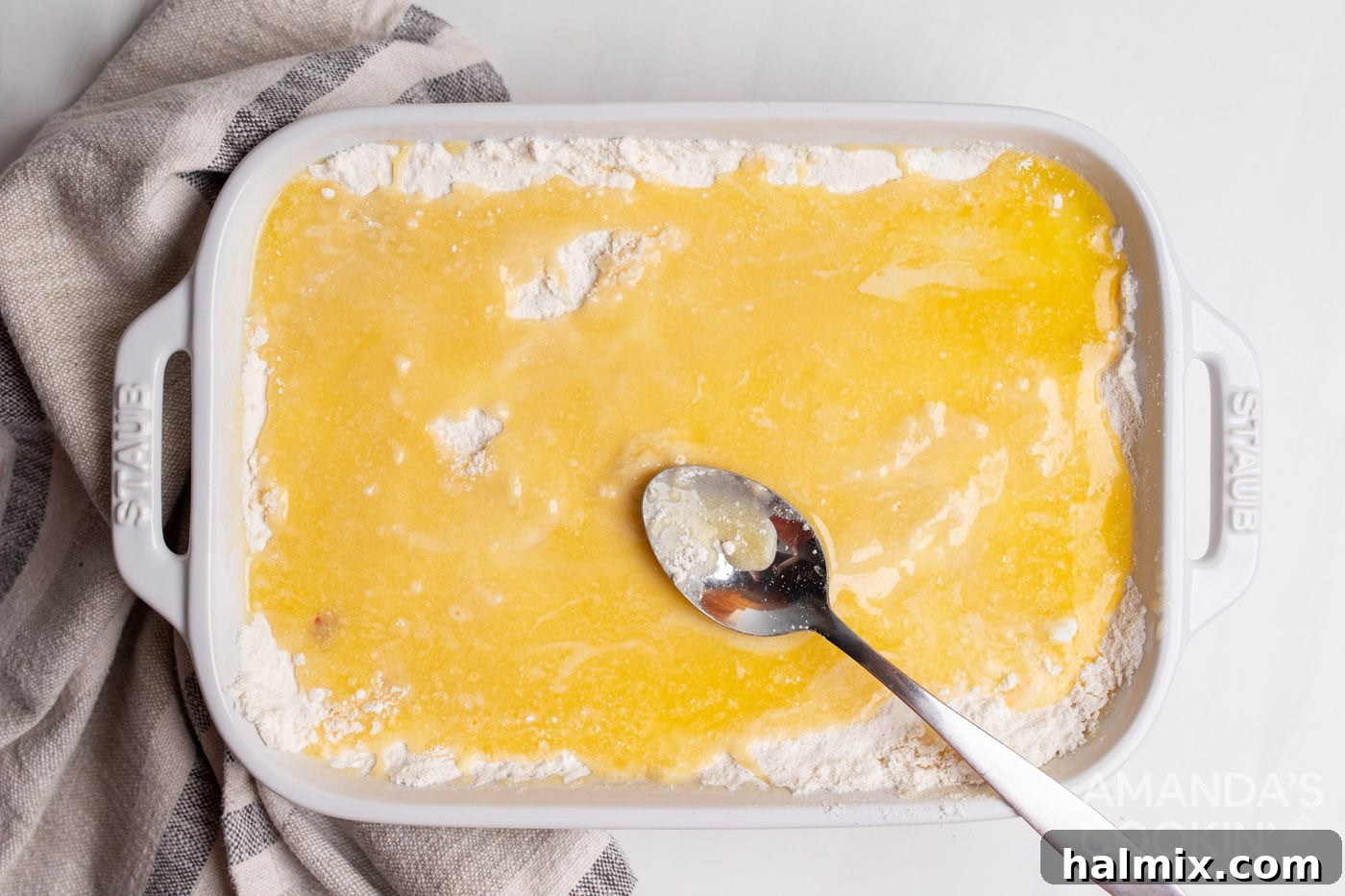spooning butter over cake mix in a casserole dish