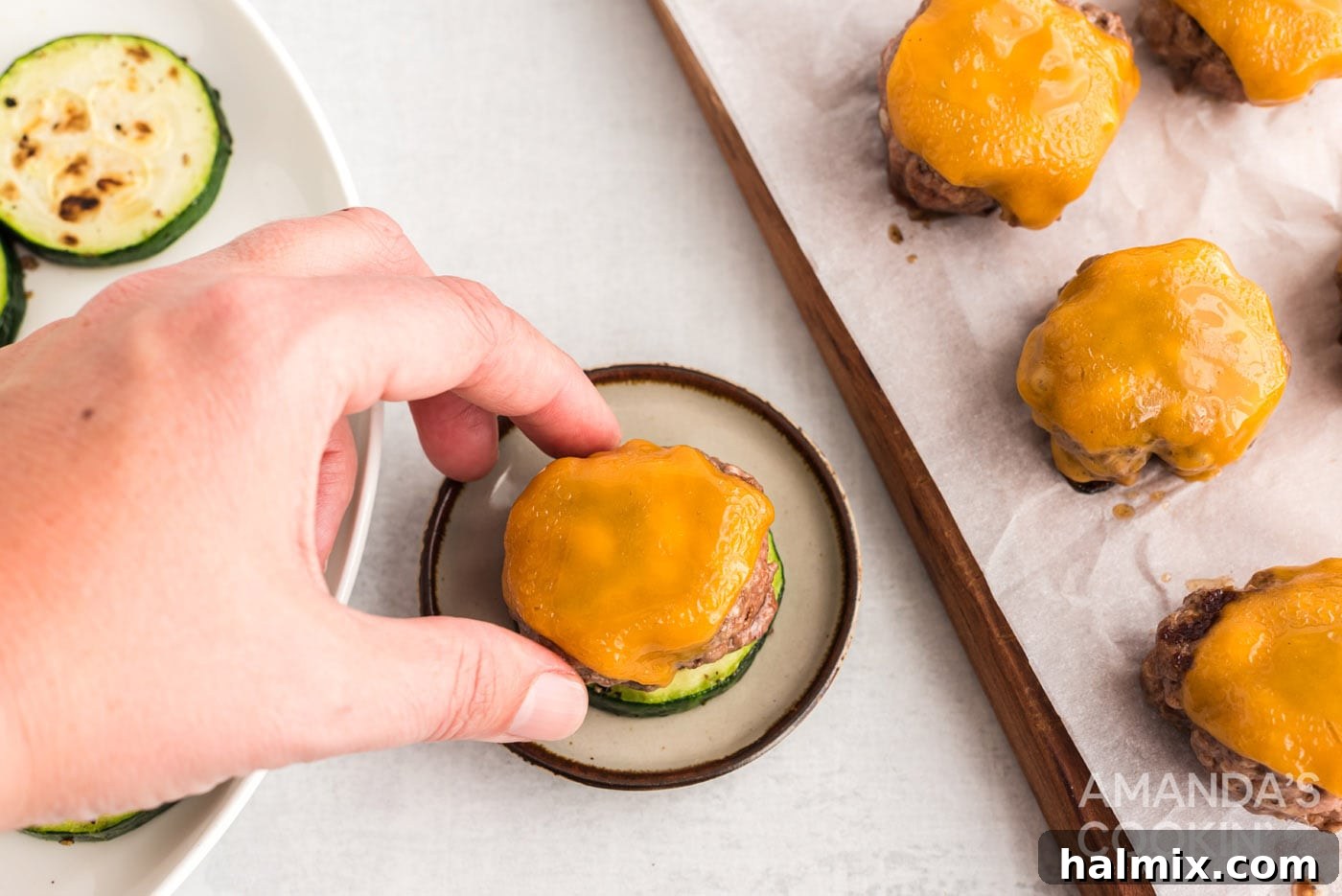 Zucchini Stackers 12 Hand placing a mini cheeseburger on a zucchini round