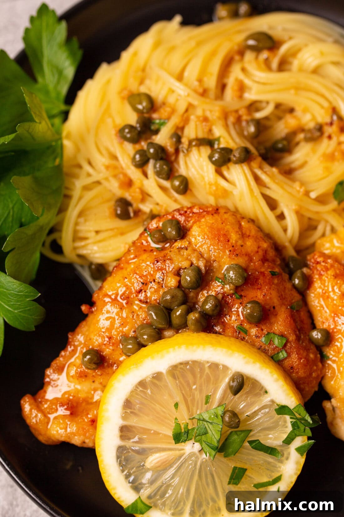 Zesty Lemon Caper Chicken 3 Close-up of Chicken Piccata served with spaghetti, garnished with parsley and lemon