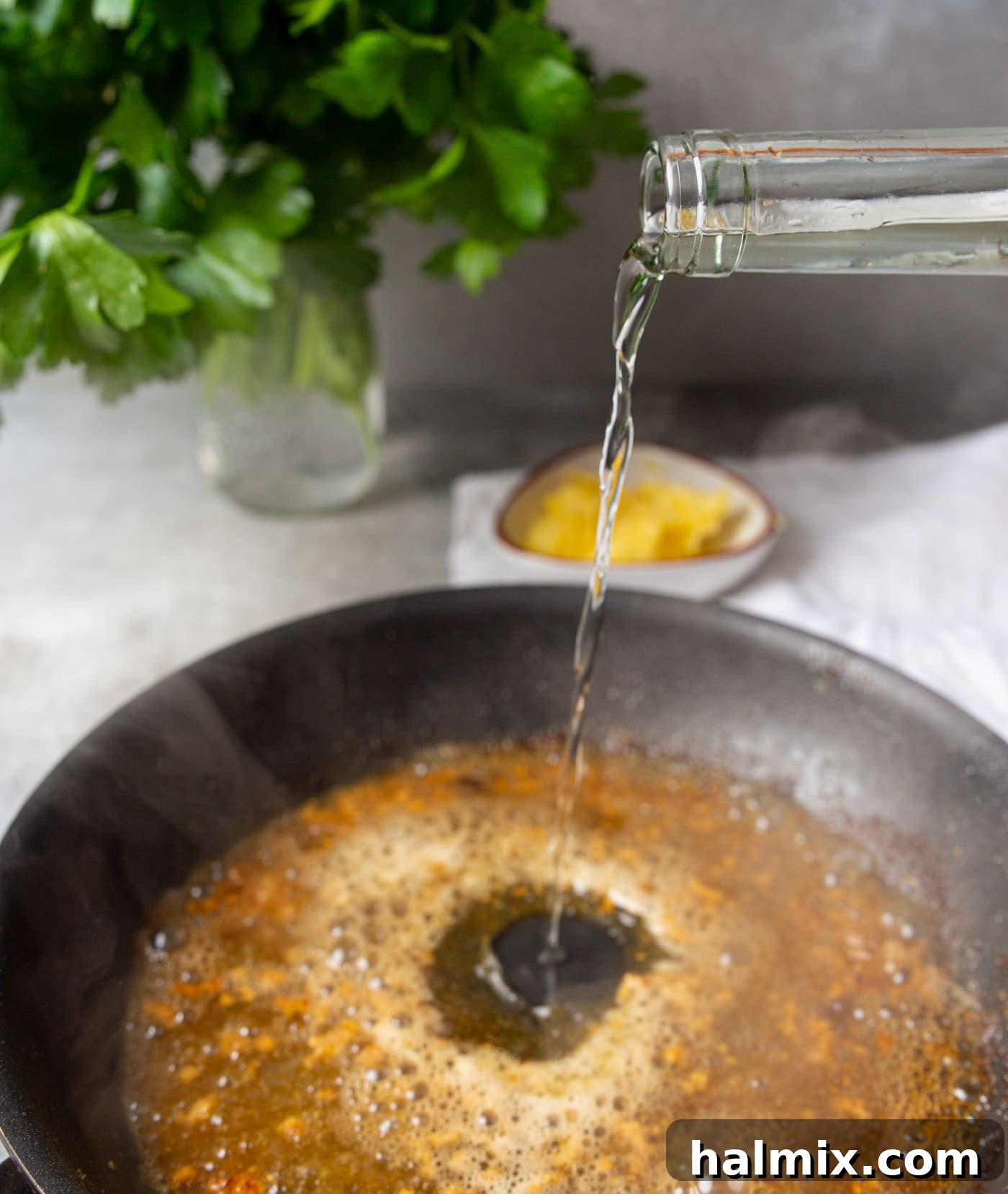 Zesty Lemon Caper Chicken 7 Pouring white wine into a skillet with garlic and butter