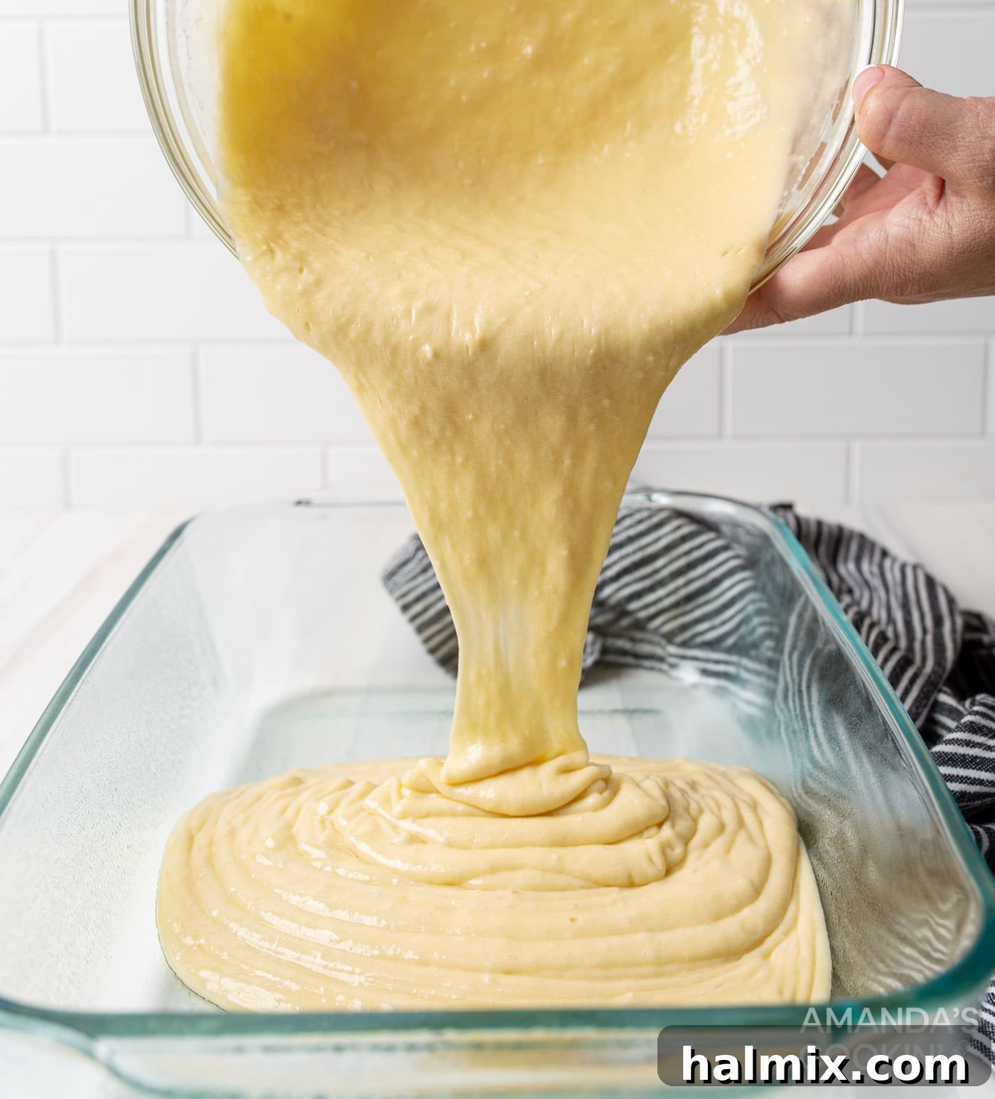 pouring prepared yellow cake batter into a 9x13 inch baking pan