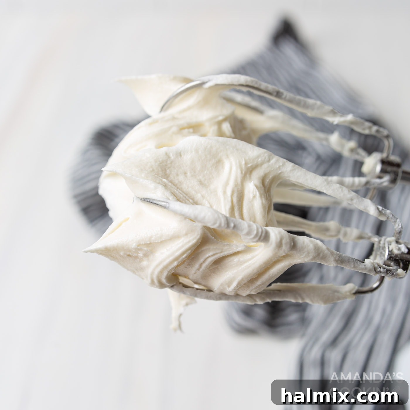 creamy, fluffy homemade cream cheese frosting on a whisk attachment after being fully mixed