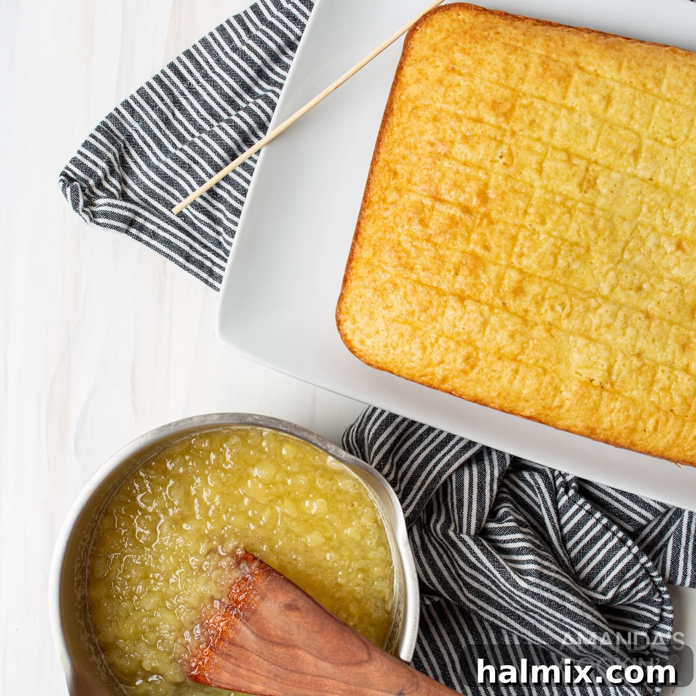 hand pouring warm pineapple mixture over a freshly baked, still warm yellow cake with holes poked into it