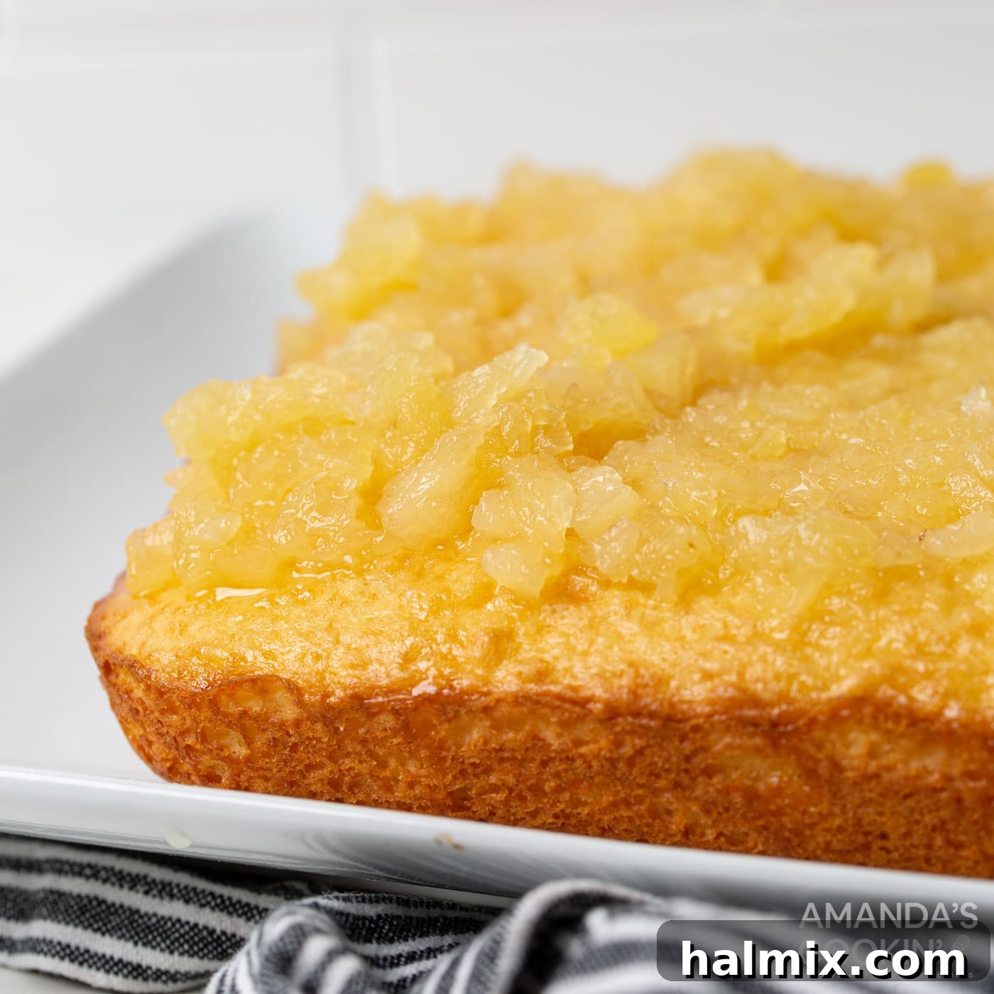 close-up of pineapple chunks resting on top of the infused yellow cake, showing the absorbed liquid