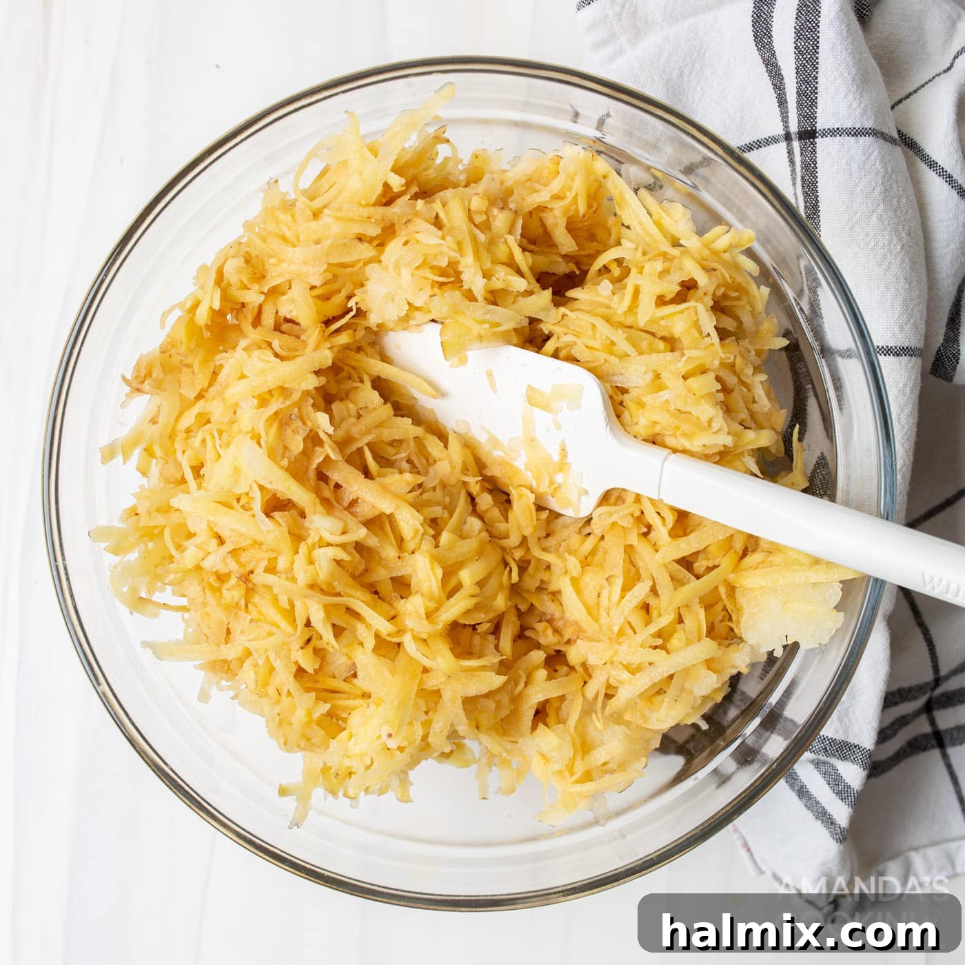 Coarsely grated potatoes and onion in a colander, draining excess liquid