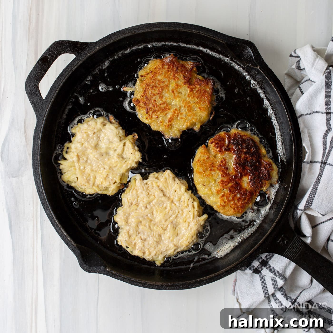 Potato pancake patties frying in a hot skillet with oil and butter, sizzling to a golden crisp