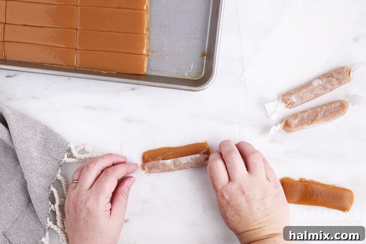 Individual microwave caramels being wrapped in squares of parchment paper.