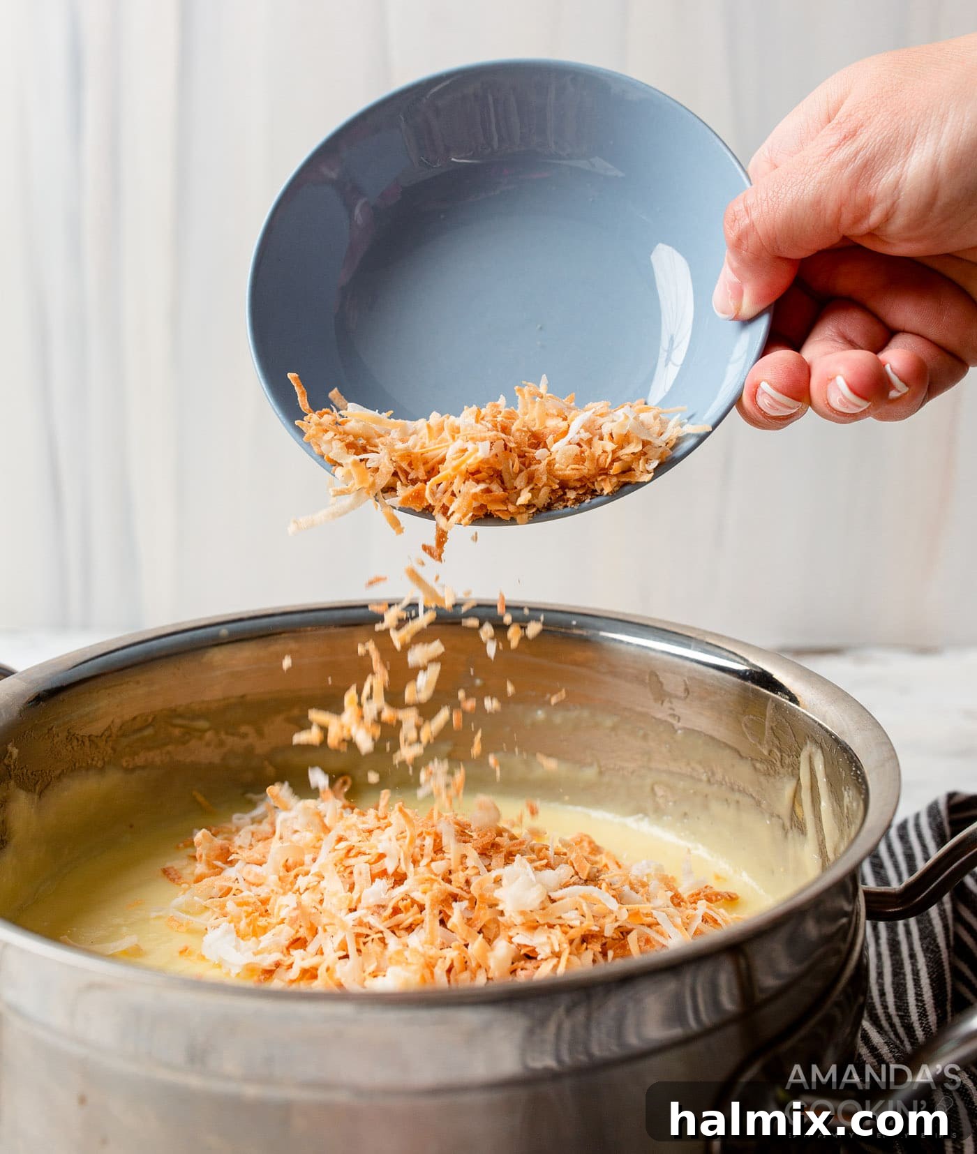 adding shredded coconut to coconut custard in a saucepan