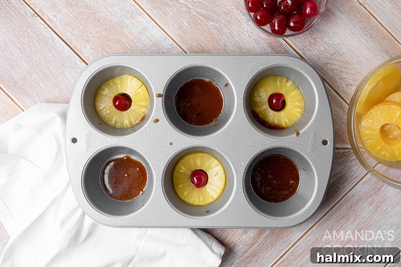 Little Rings of Paradise 5 Pineapple rings and maraschino cherries arranged over butter and brown sugar in a jumbo muffin tin.
