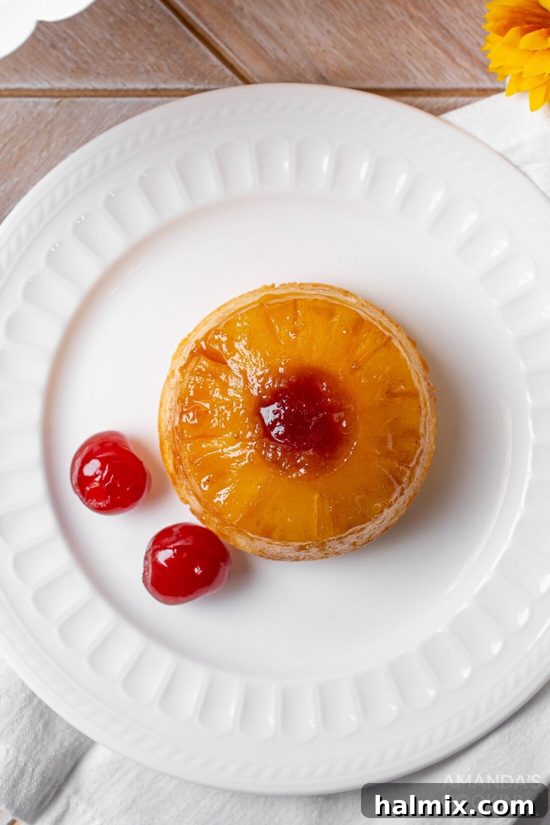 Little Rings of Paradise 8 A single mini pineapple upside down cake, perfectly baked and golden, sitting on a plate.