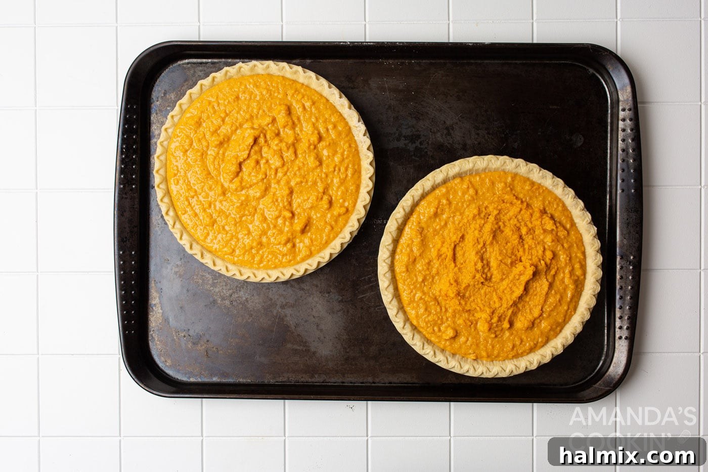 Two sweet potato pies cooling on a baking sheet, ready for whipped cream