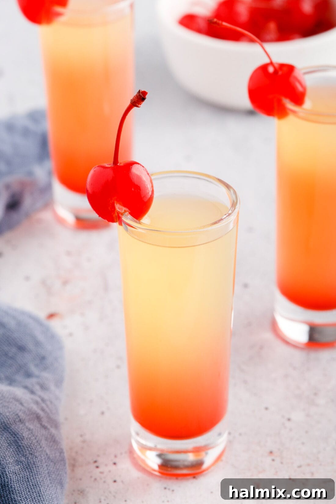 Pineapple Upside Down Cake Shot garnished with a cherry, showcasing vibrant layers.