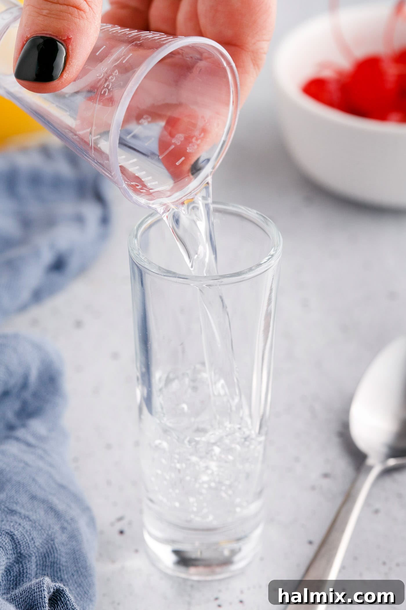 Pouring vanilla vodka into a tall shot glass.