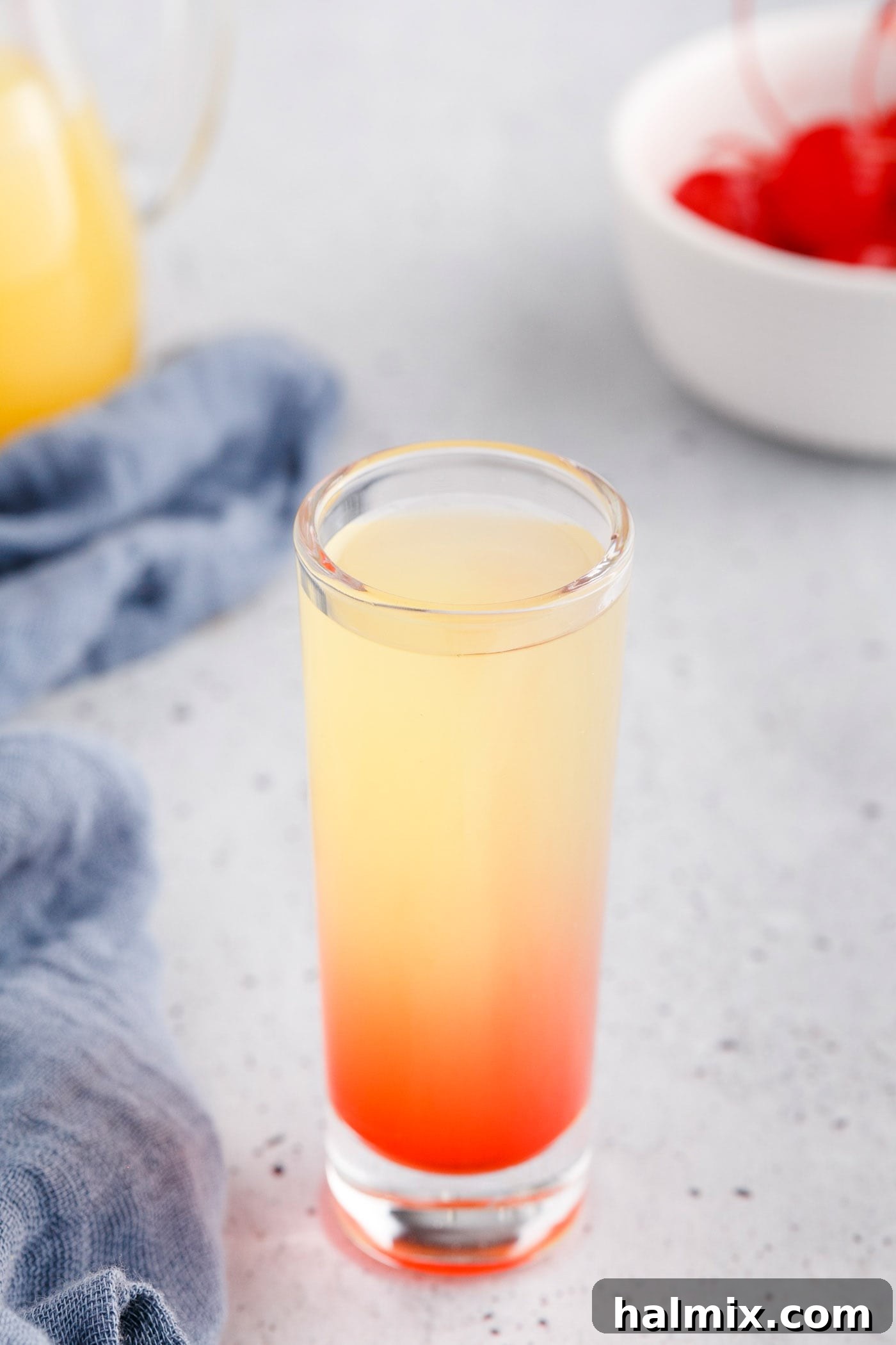Shot glass with distinct layers of grenadine, pineapple juice, and vanilla vodka.