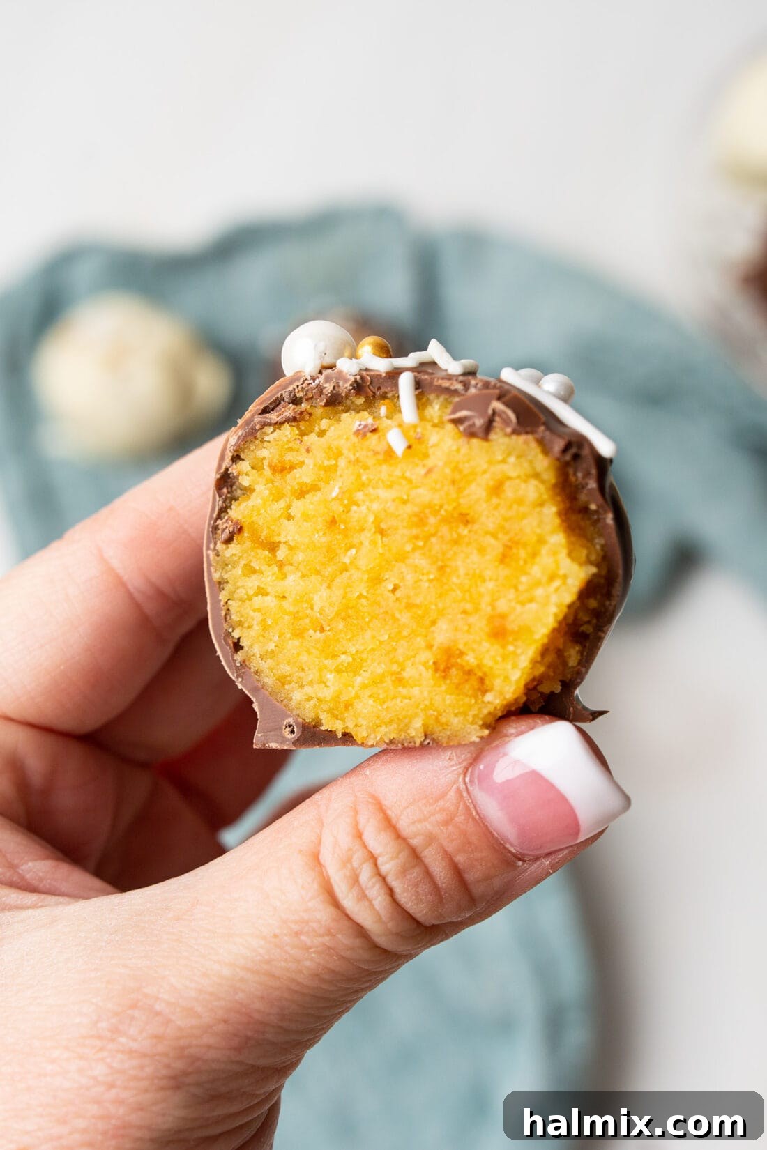 Cake Truffles 5 A hand holding a perfectly split cake ball, revealing its moist interior.