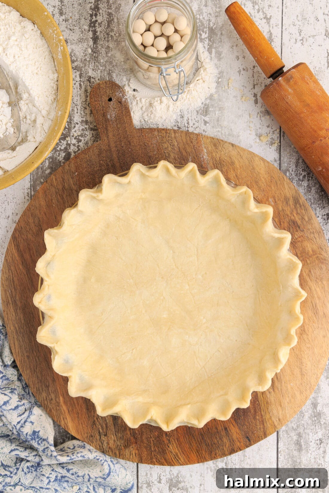 Golden, flaky pie crust on a rustic cutting board, ready for filling