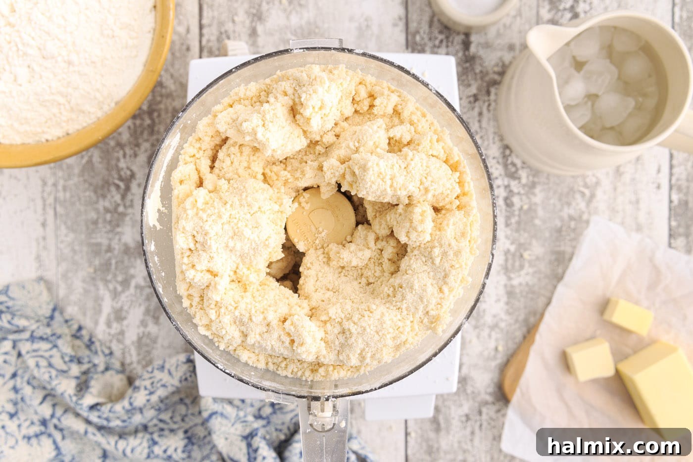 Pie dough clumping together in a food processor bowl after adding water