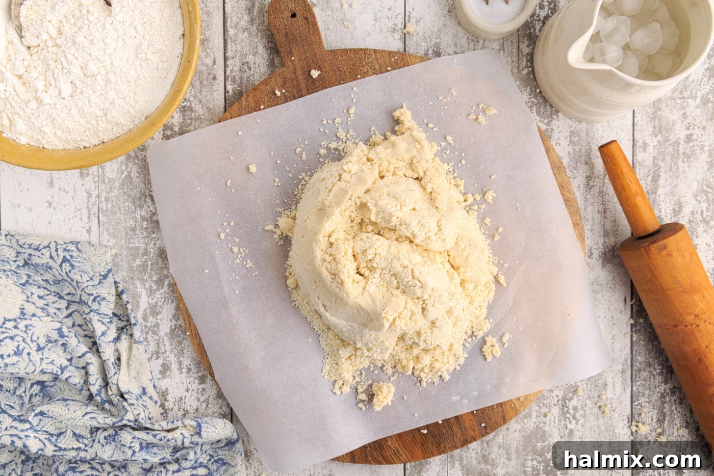 Pie dough ball resting on parchment paper on a cutting board