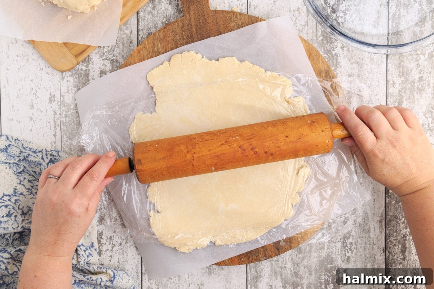 Rolling pin flattening pie dough between two sheets of parchment paper