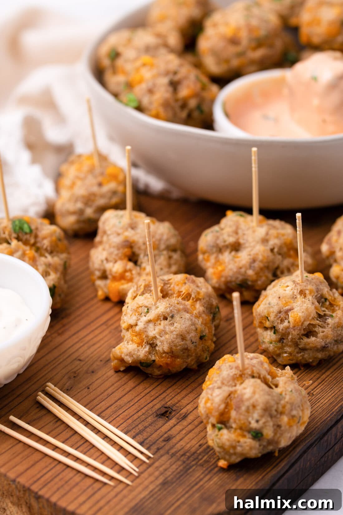 Savory Sausage Bites 2 Four ingredient sausage balls on toothpicks, beautifully arranged on a white platter for easy serving at a party or holiday event.