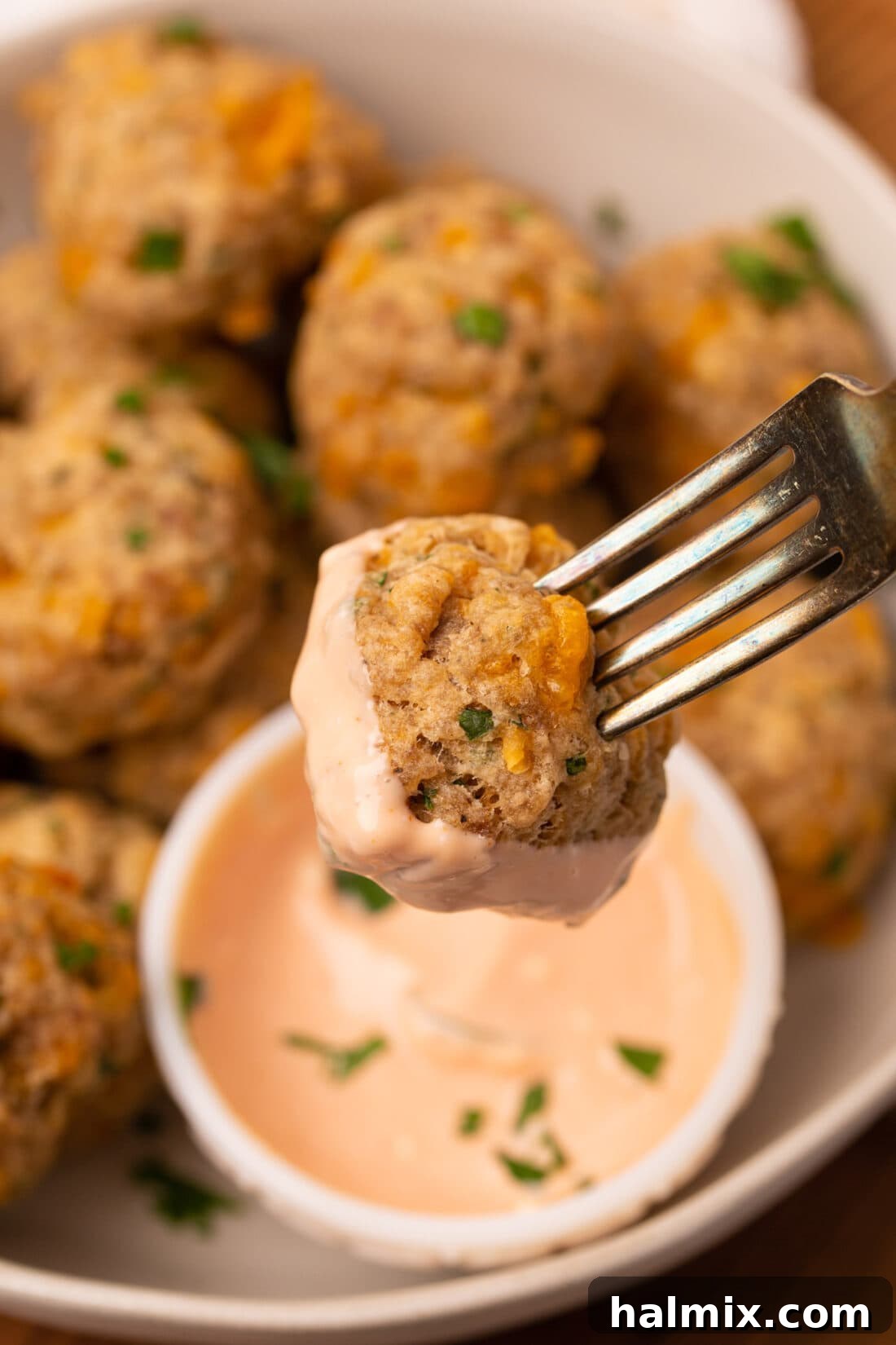 Savory Sausage Bites 3 Close-up of a sausage ball dipped in a rich, flavorful sauce, emphasizing its perfect texture and taste.