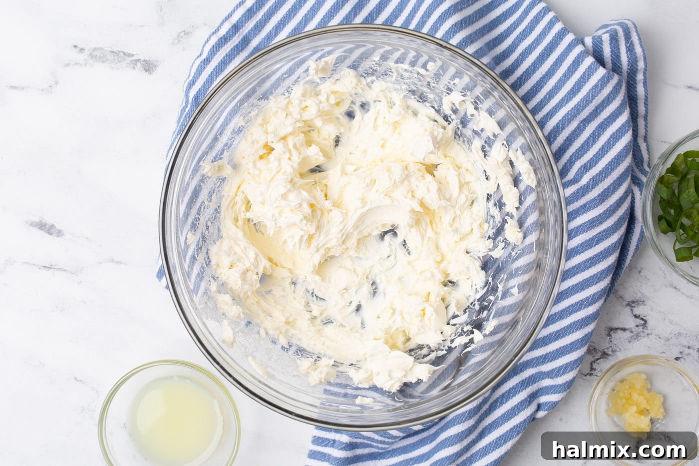 Softened cream cheese being whipped in a large mixing bowl.