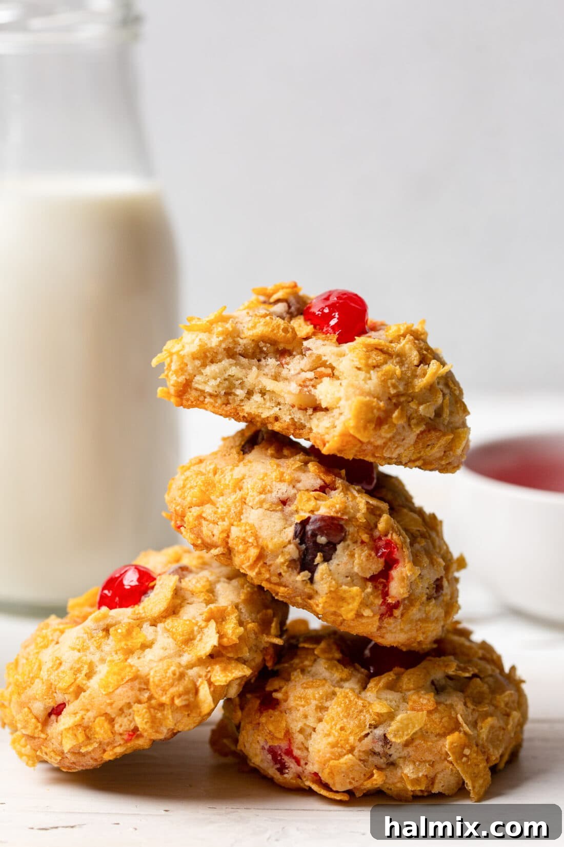 A stack of golden Cherry Wink Cookies with their distinct cornflake coating and red cherry centers, embodying old-fashioned holiday cheer.