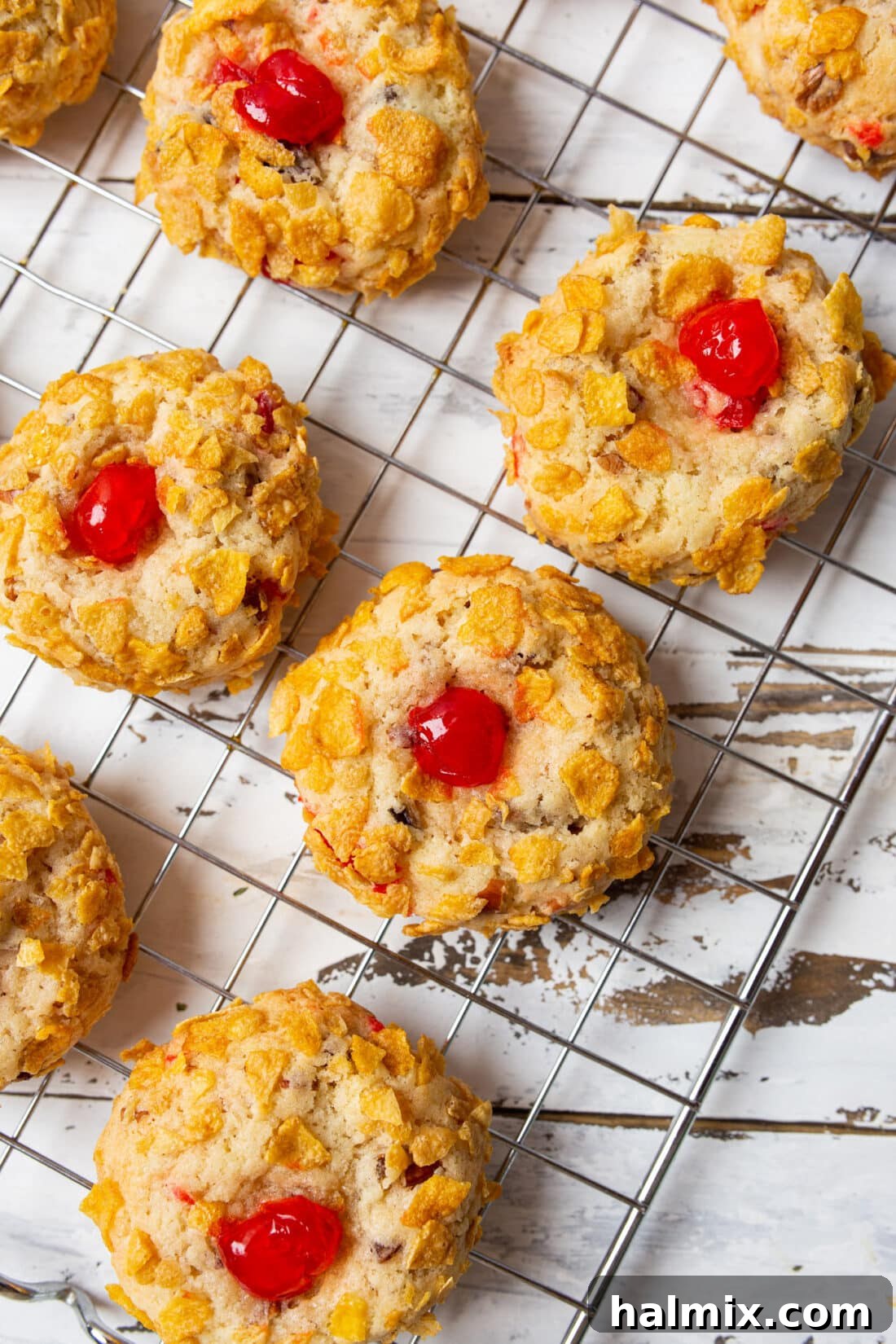 Freshly baked Cherry Wink Cookies cooling on a wire rack, showcasing their perfectly golden cornflake crust and tempting cherry centers.