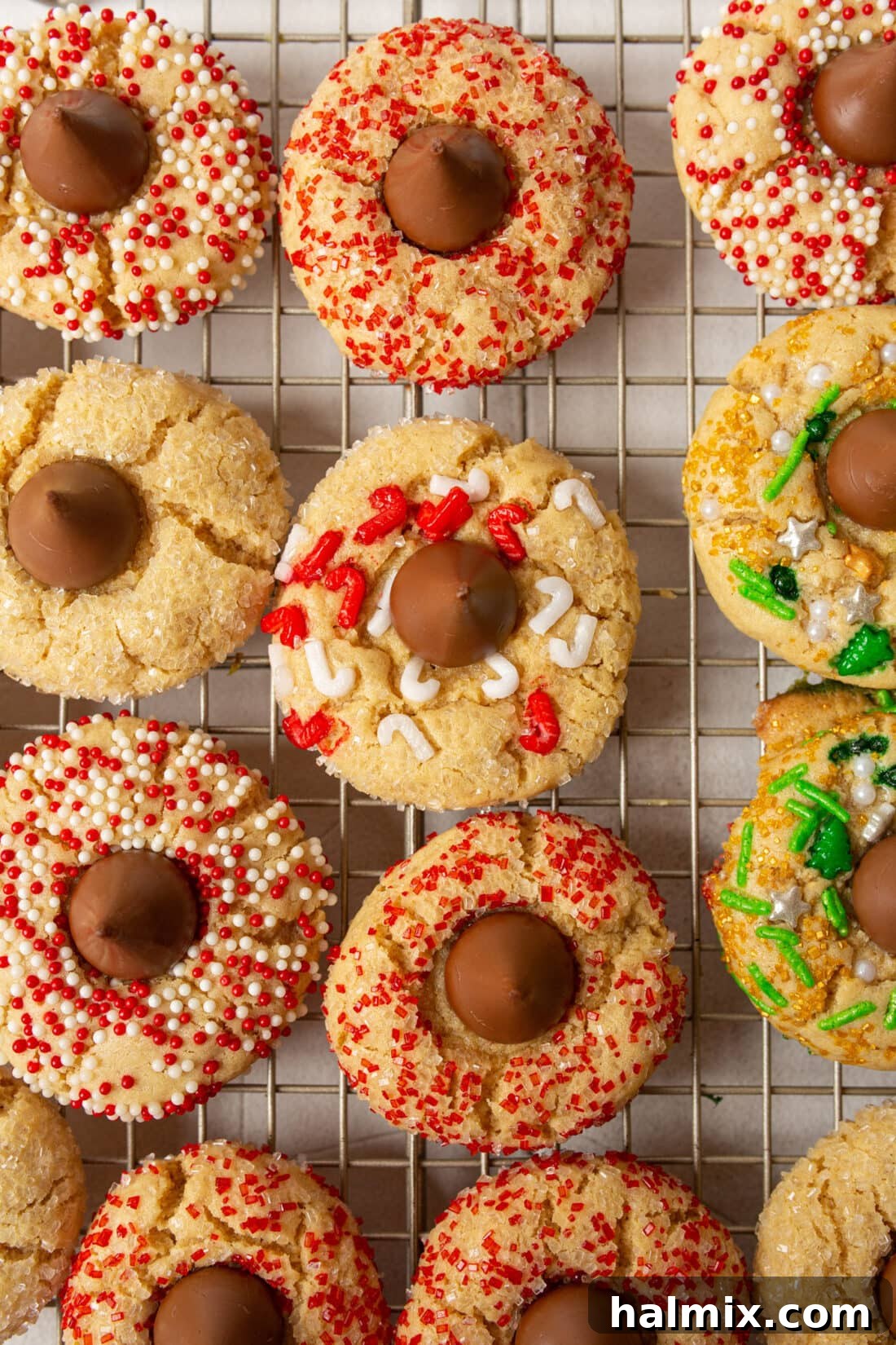 Cooling rack filled with freshly baked Christmas Kiss Cookies adorned with festive sprinkles and Hershey's Kisses