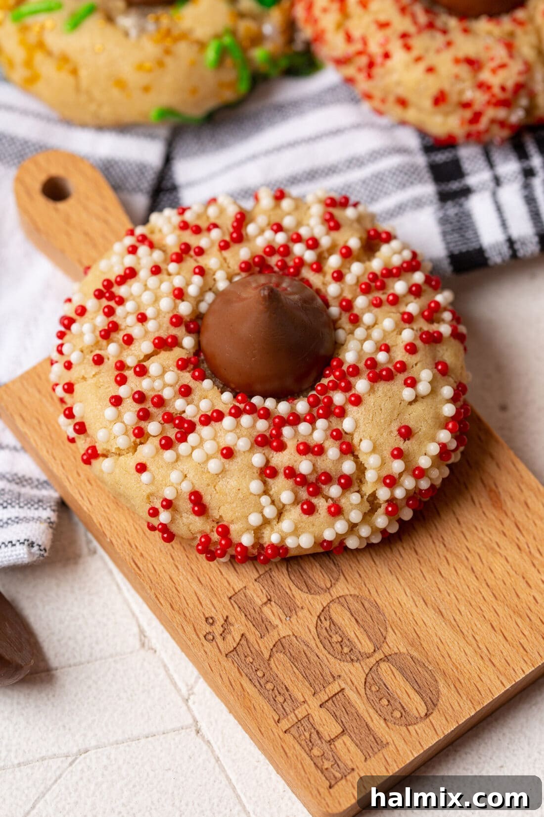 Christmas Kiss Cookies displayed on a wooden cutting board with a festive background