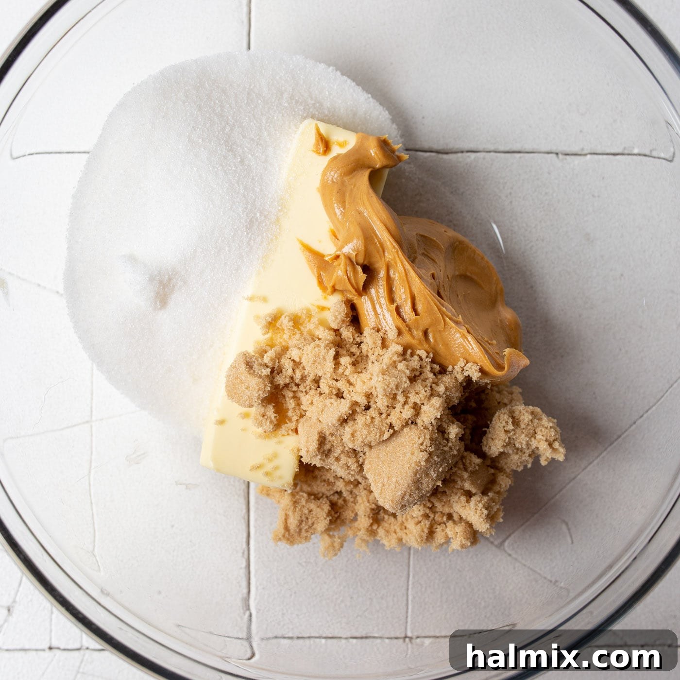 Peanut butter, brown sugar, and granulated sugar being beaten together in a large mixing bowl