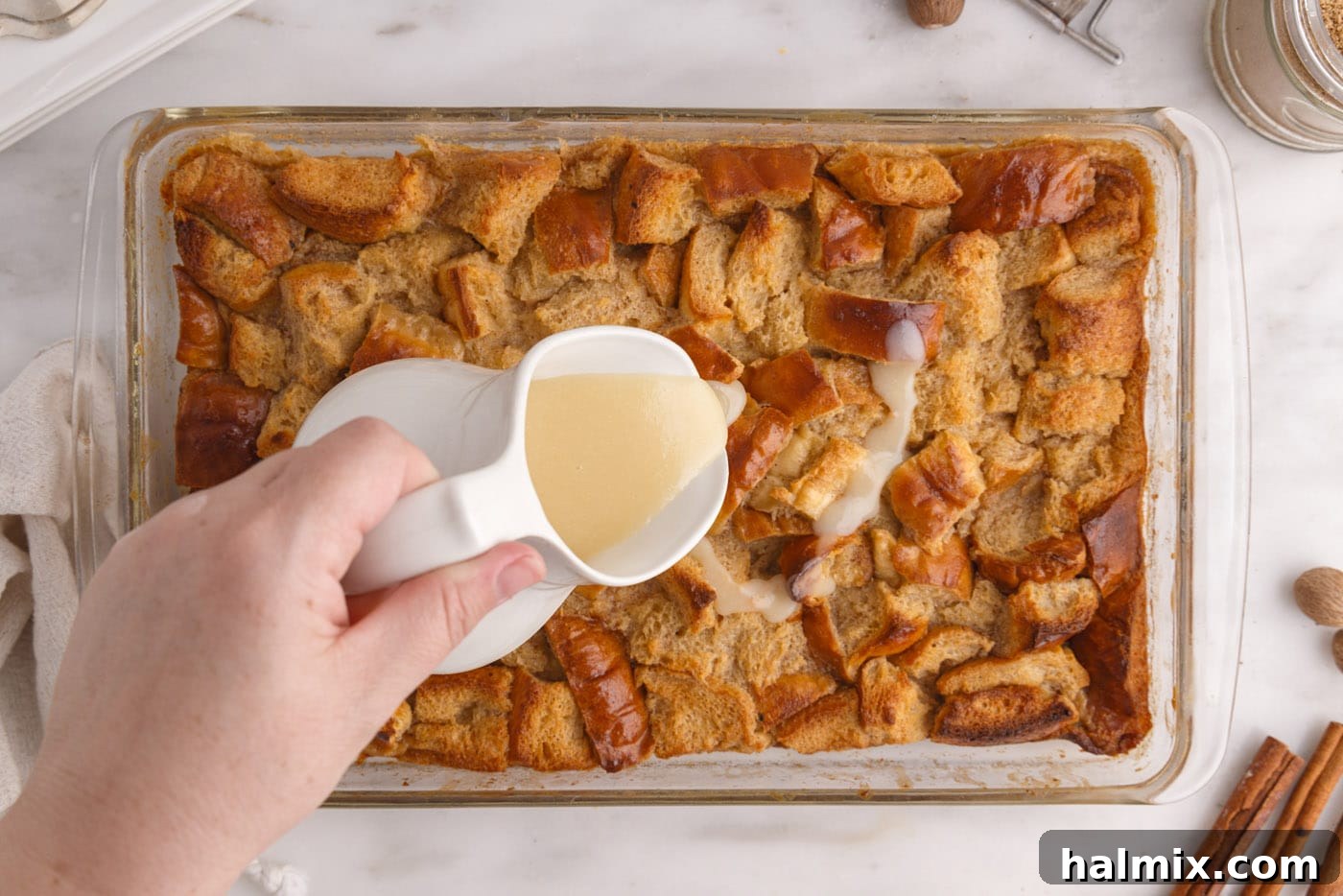 pouring vanilla sauce over bread pudding