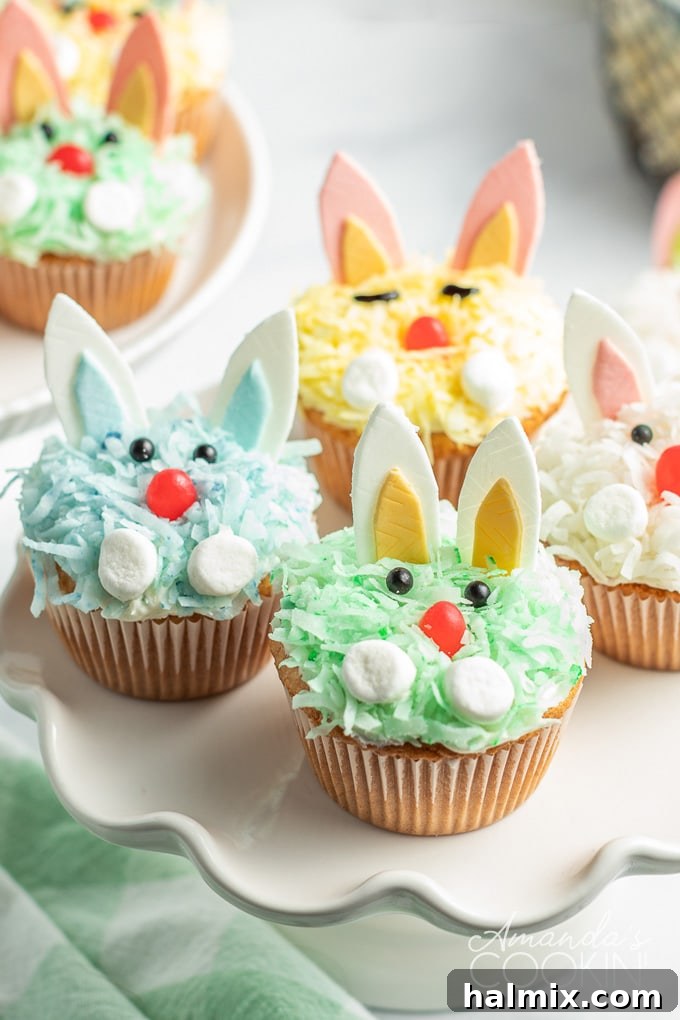 These charming Easter Bunny Cupcakes, crafted with ease from a boxed cake mix and simple decorations, are a delightful addition to any festive holiday table. A close-up shot of a plate laden with beautifully decorated bunny rabbit cupcakes, showcasing their varied colored coconut coatings and cheerful expressions, ready to be enjoyed.