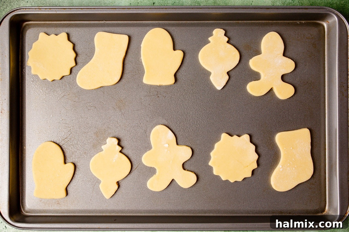 Brushstroke Delights 7 Unbaked holiday-themed sugar cookies, cut into shapes, are arranged neatly on a baking sheet.