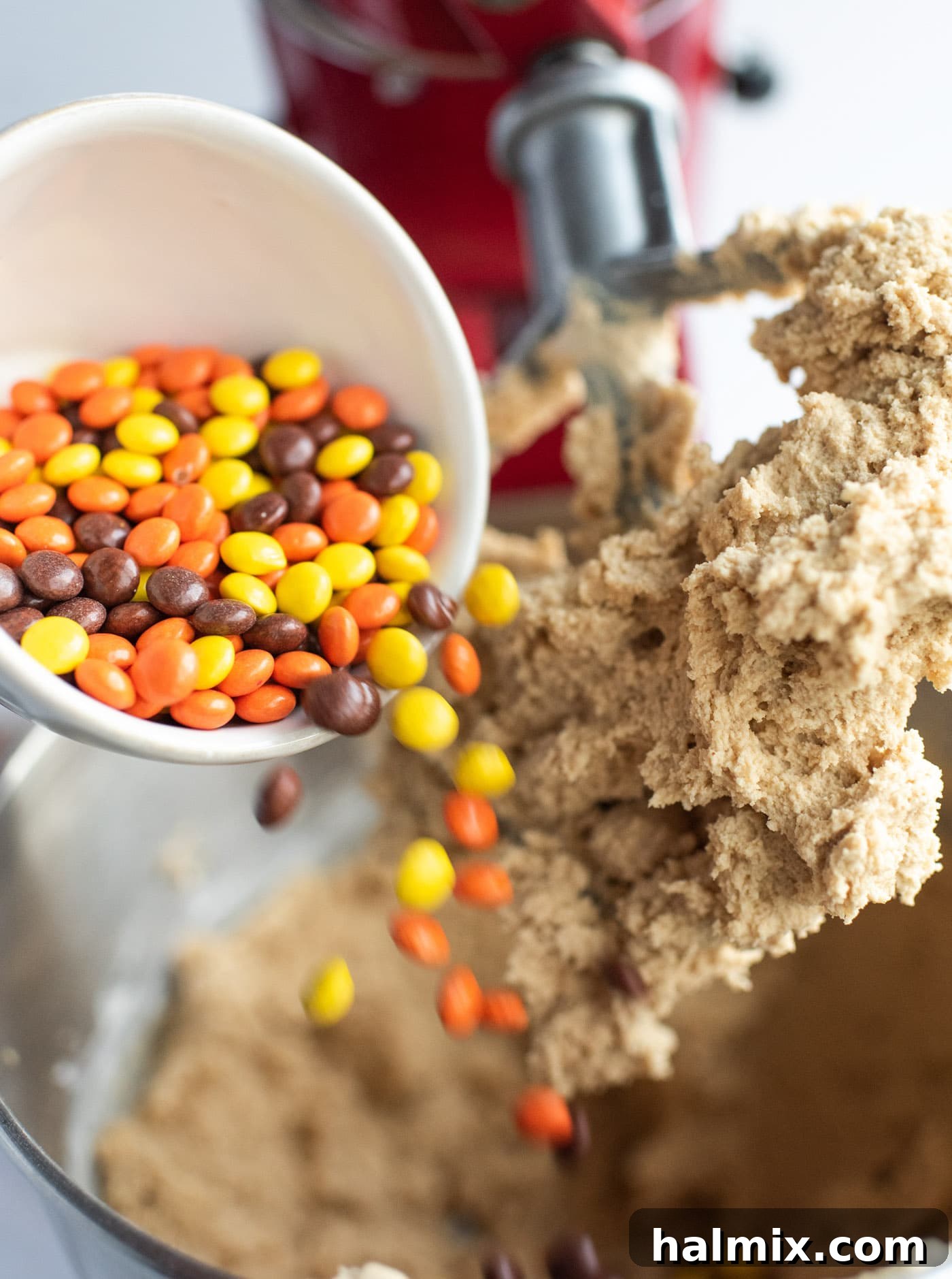 Pouring Reese's pieces into cookie dough