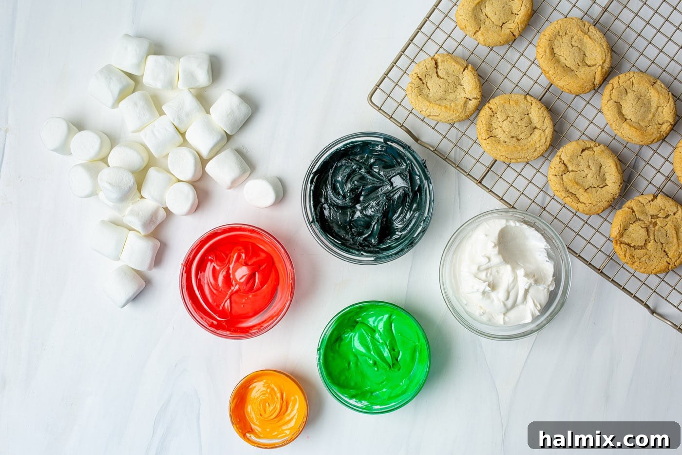Bowls of colorful icing, marshmallows, and sugar cookies laid out for decoration.
