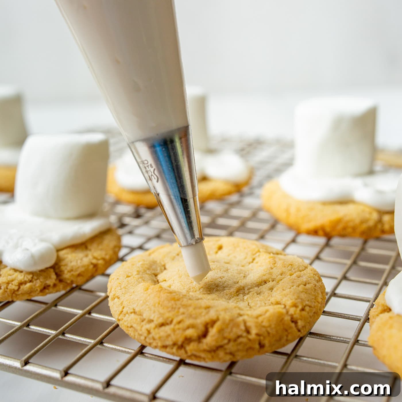 Piping white icing onto a sugar cookie to create the melted snow base for the snowman.