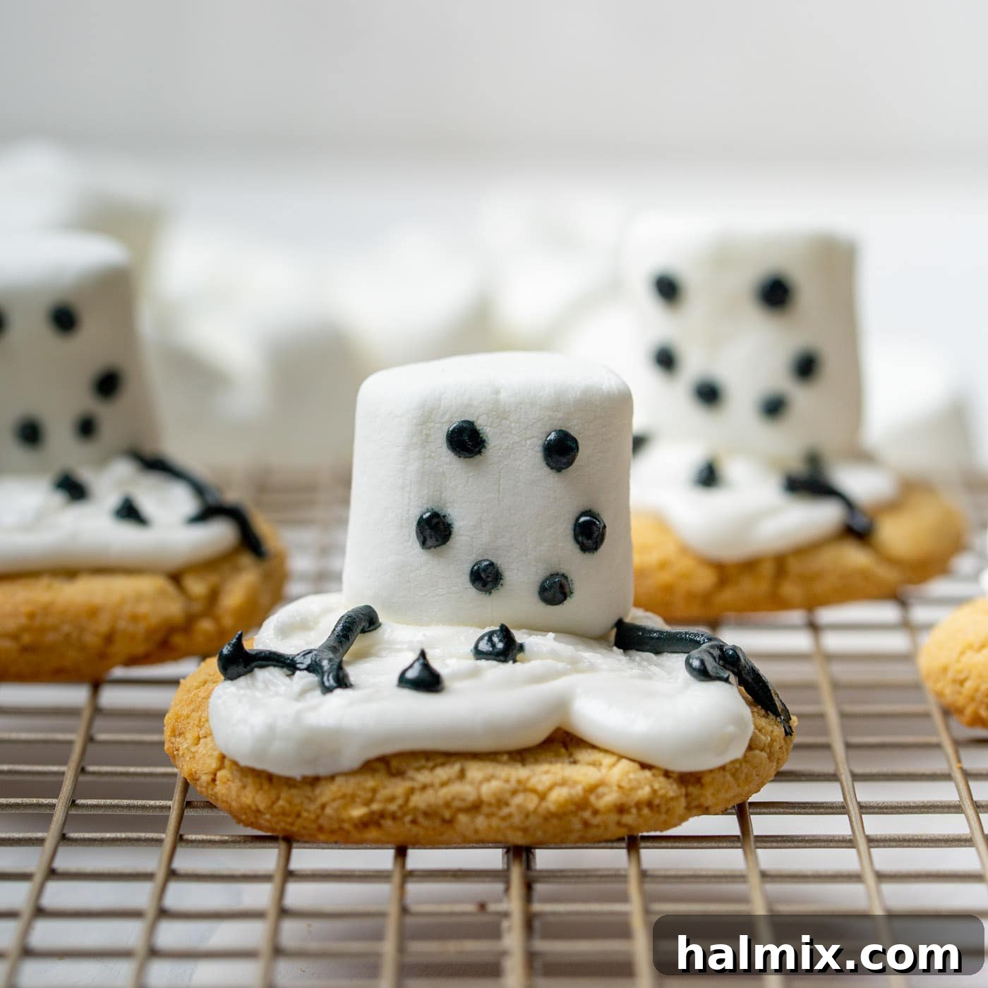 Adding facial features like eyes, mouth, buttons, and arms using black icing on the snowman cookies.