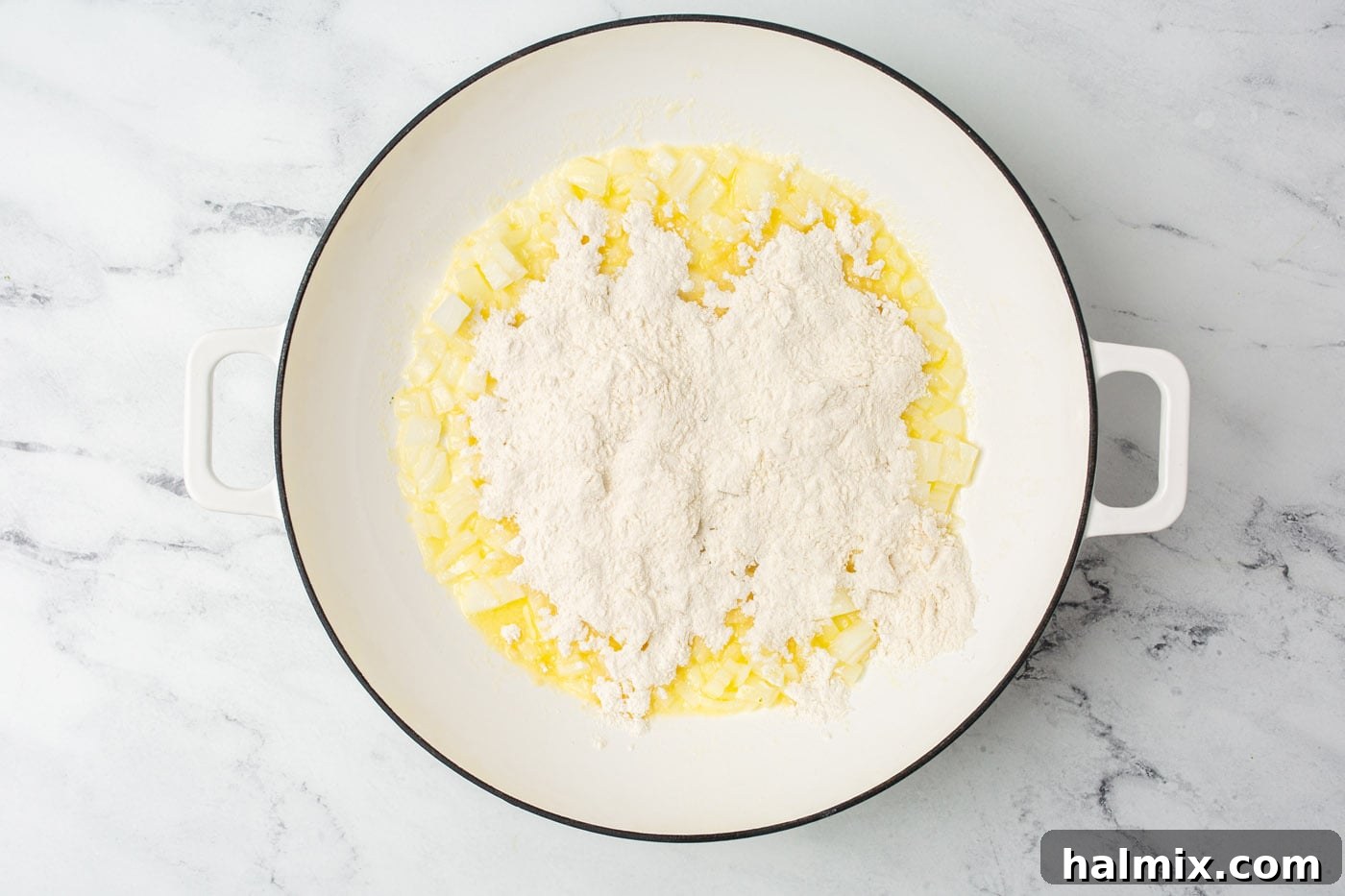 Sprinkling flour over sautéed onions and melted butter in a saucepan.