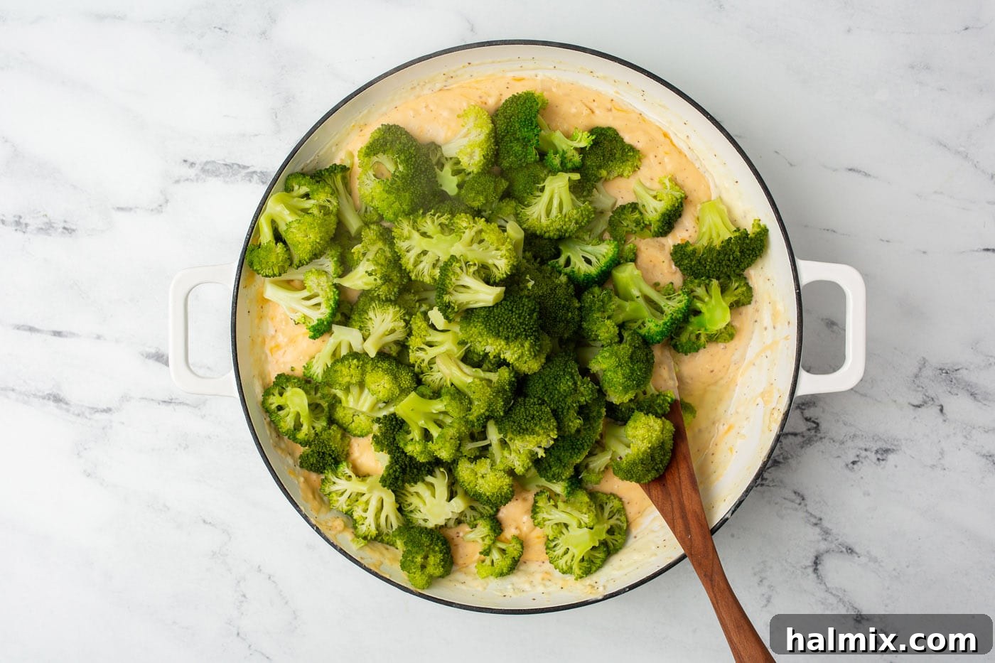 Broccoli florets fully coated in a creamy cheddar cheese sauce, ready to be transferred.