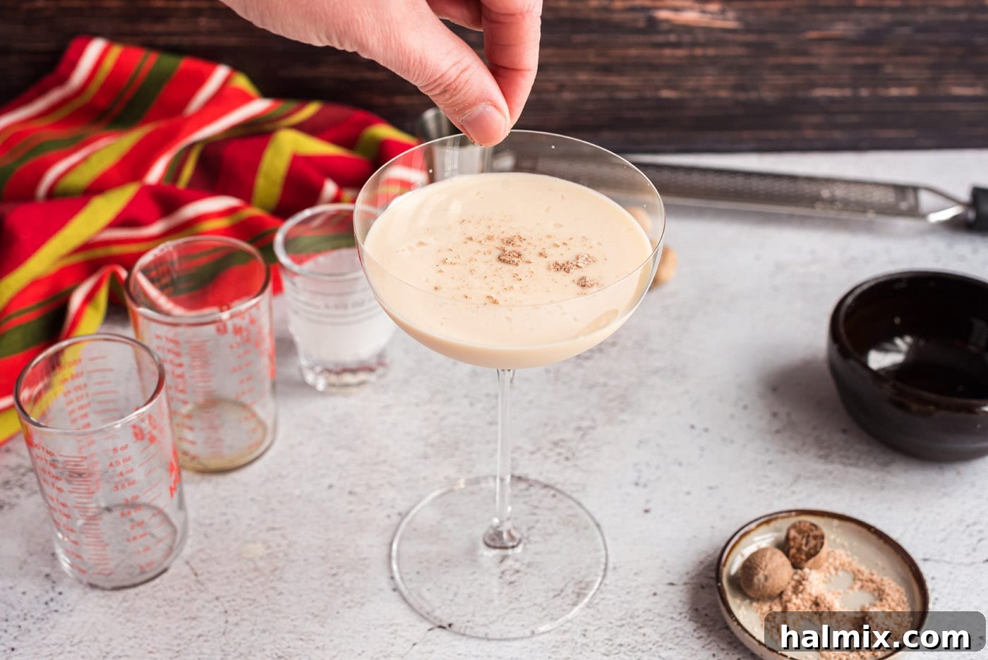 Velvet Brandy Dream 9 hand sprinkling ground nutmeg on top of brandy alexander cocktail