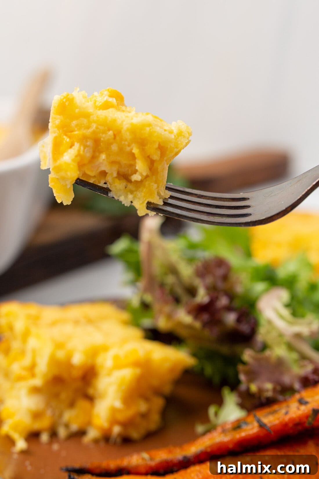 A fork taking a piece of corn casserole from the pan, showing its soft and warm interior.