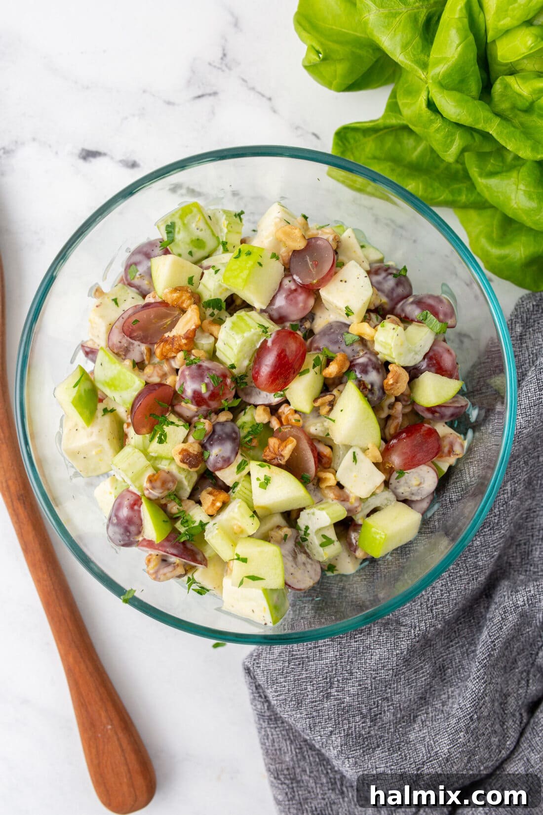 A large glass bowl filled with colorful Waldorf Salad, ready to be served at a gathering.