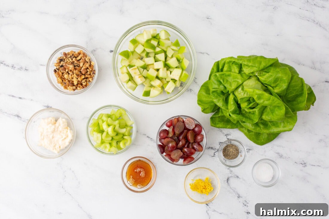 Fresh ingredients laid out for making Waldorf Salad, including apples, grapes, celery, walnuts, and dressing components.