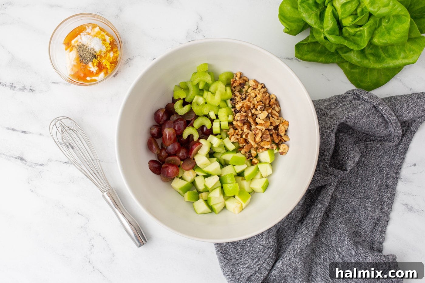 Apples, celery, walnuts, and grapes neatly arranged in a bowl before dressing.